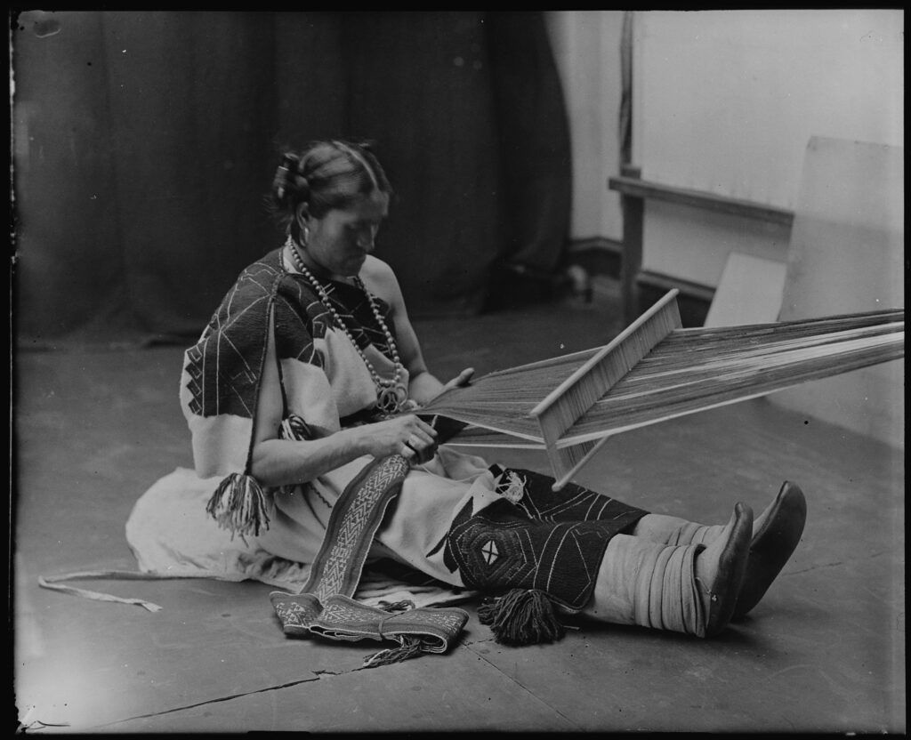 Photograph of Wewha of Zuni seated at a loom, weaving